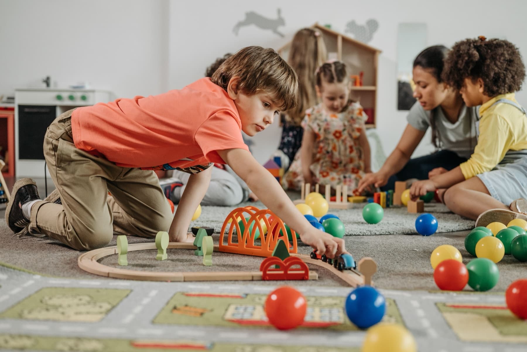 Children and educators exploring a train track together in an early learning room